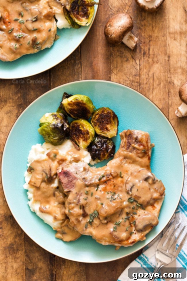 Pork chop with gravy, mashed potatoes, and Brussels sprouts on a blue plate