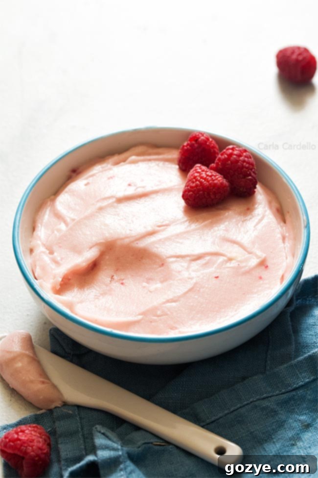 Raspberry cream cheese frosting in white bowl, perfectly swirled