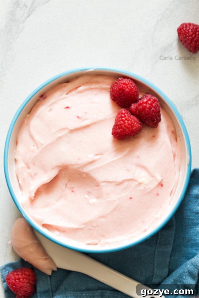 White bowl filled with fluffy pink raspberry cream cheese frosting