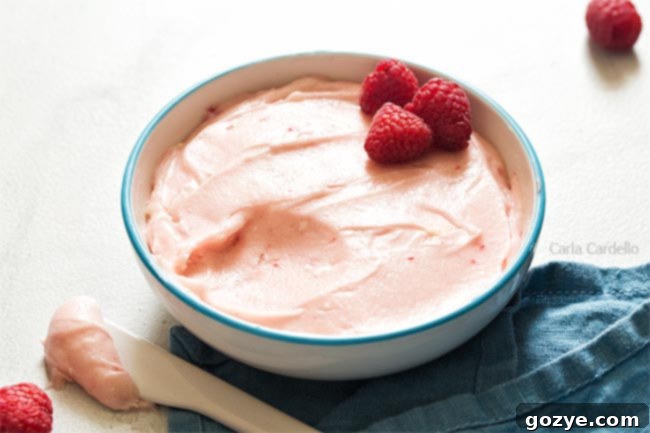 Raspberry cream cheese frosting in a white bowl, showing its pink color and creamy texture