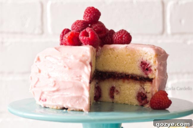 Lemon raspberry cake on a turquoise cake stand with a slice removed