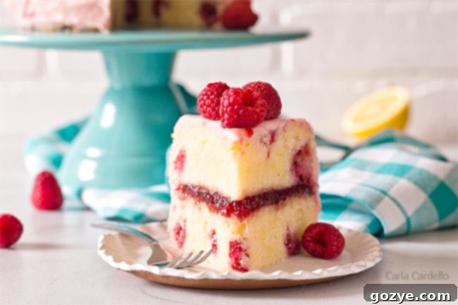 A slice of lemon raspberry cake on a white plate, showing the layers