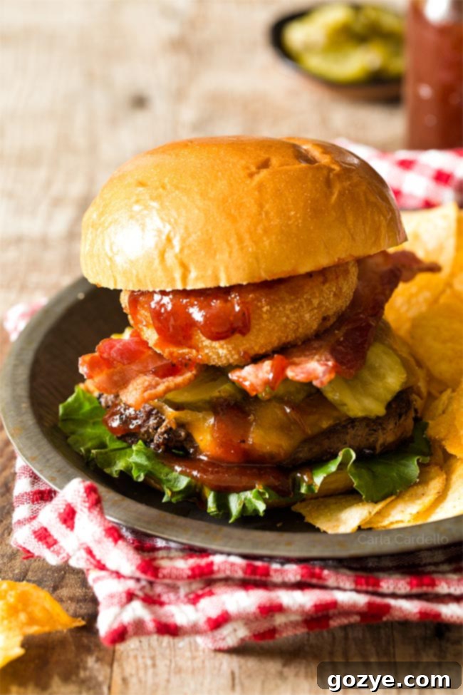 Assembled BBQ Bacon Burgers on a plate with potato chips, ready to serve