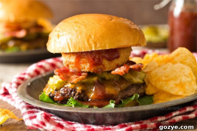Close-up of a stacked BBQ Bacon Burger with chips and a red checkered napkin