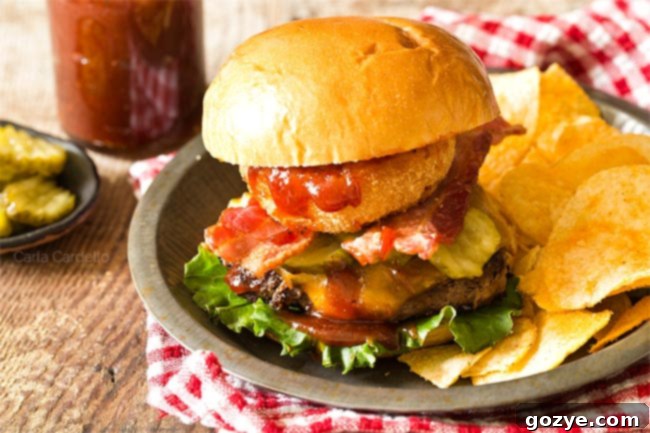 Two BBQ Bacon Burgers on a plate with potato chips and a red checkered napkin, presented beautifully