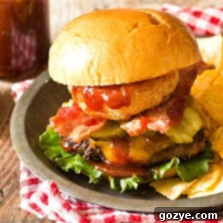 BBQ Bacon Burgers on a plate with chips and a red checkered napkin, ready to serve