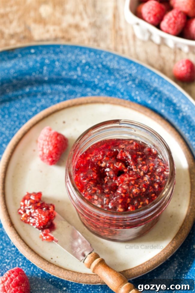 Raspberry Jam in a small jar on a plate with a knife