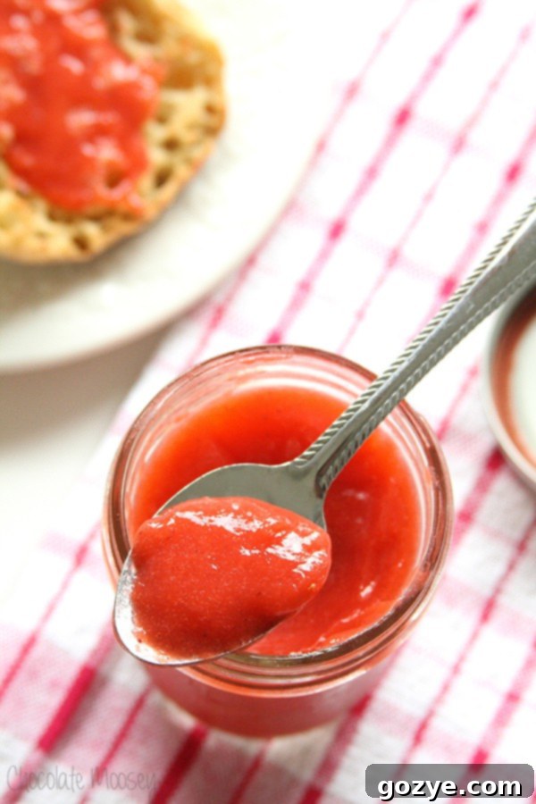 Strawberry Curd on a spoon, showcasing its smooth and vibrant texture.