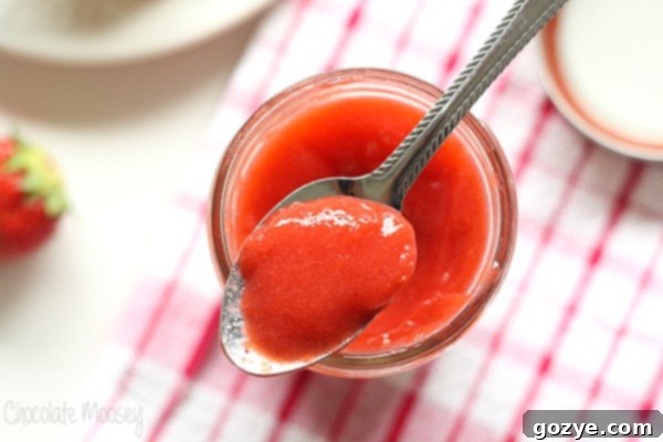 Close-up of smooth, creamy strawberry curd on a spoon.