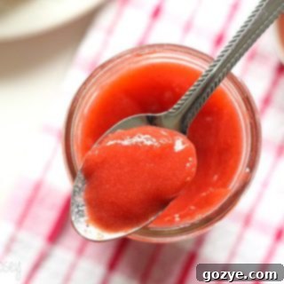 Vegan Strawberry Curd in a jar with fresh strawberries around it.