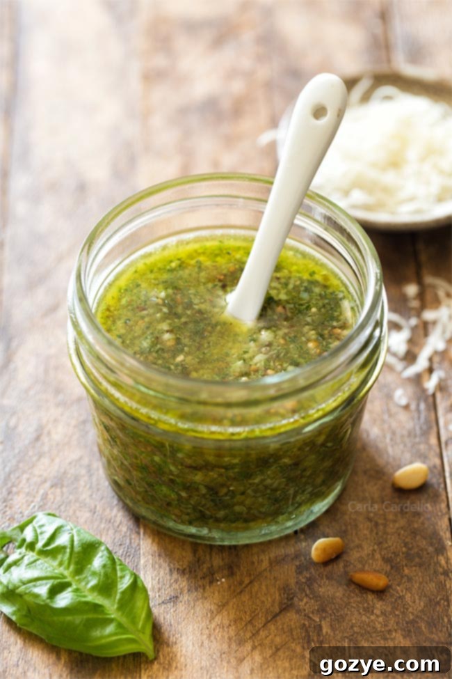 Homemade basil pesto in a small glass jar with a white spoon