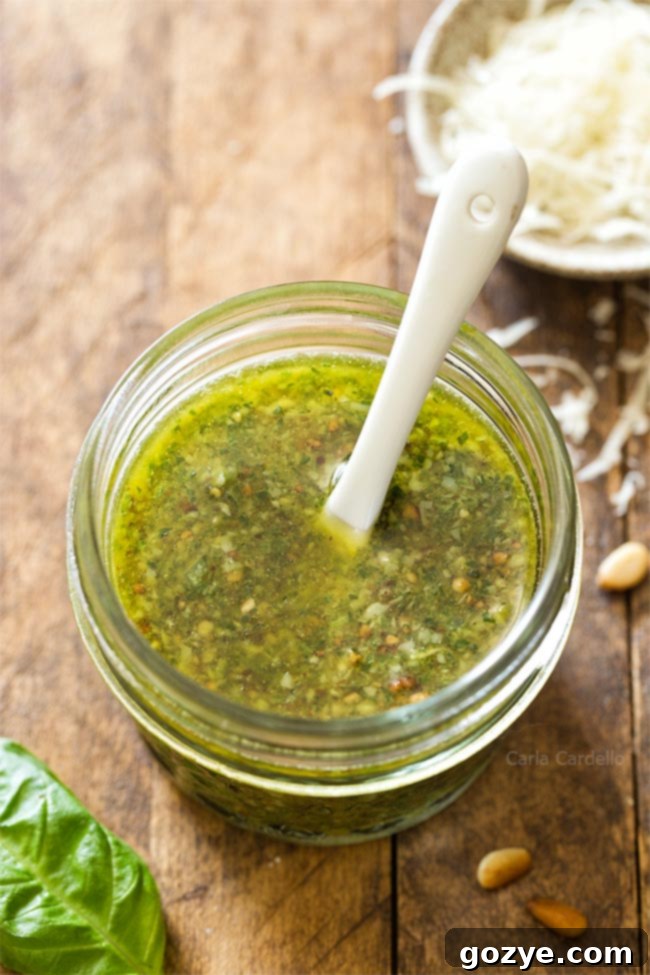 Basil pesto in a small jar with a white spoon, showcasing its vibrant green color