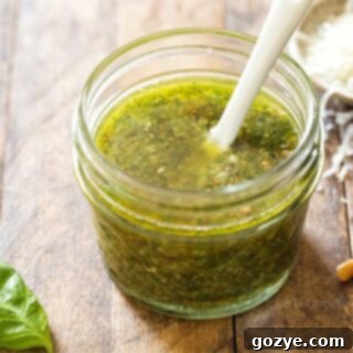 Homemade basil pesto in a small jar with a white spoon