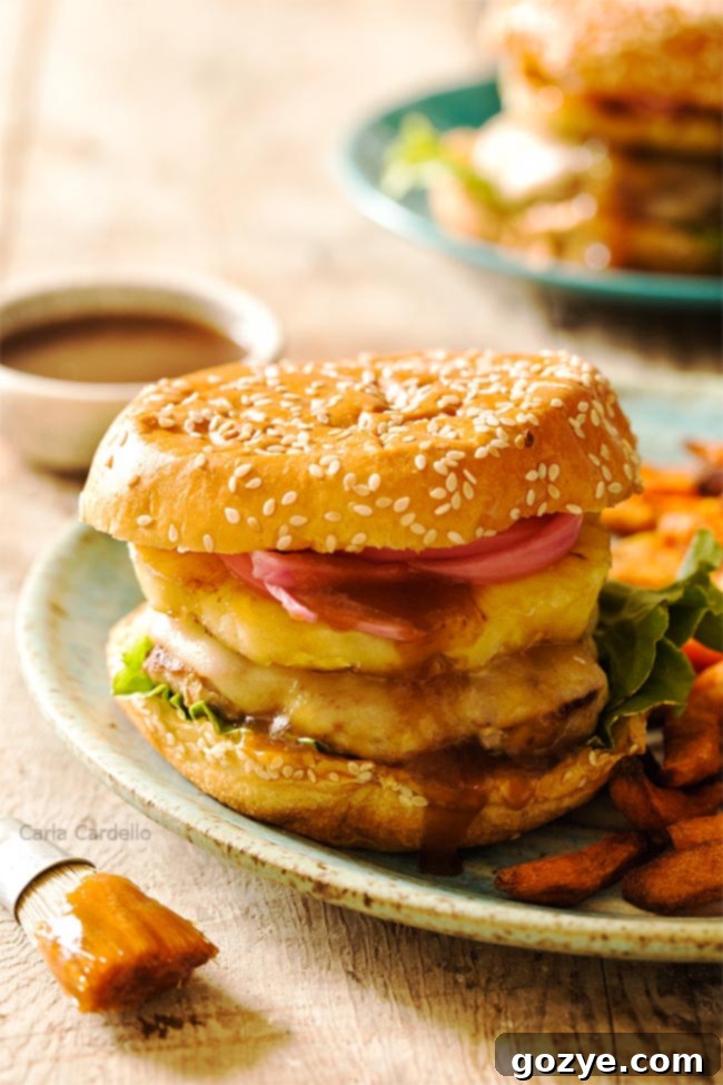 Savory Teriyaki Turkey Burgers 2 Two juicy Teriyaki Turkey Burgers on brioche buns, topped with grilled pineapple and pickled red onion, served with a side of crispy sweet potato fries on a rustic plate.
