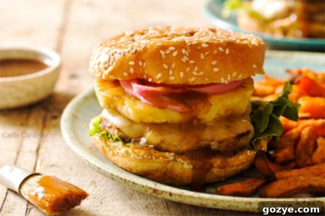 Savory Teriyaki Turkey Burgers 5 Two Teriyaki Turkey Burgers on brioche buns, served with a side of golden sweet potato fries. The burgers are topped with grilled pineapple, pickled red onion, and melted Swiss cheese, reflecting a vibrant and inviting meal.
