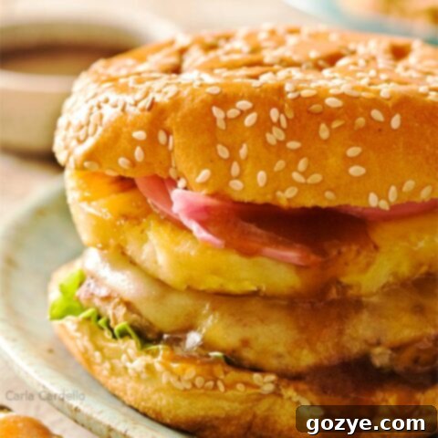 Savory Teriyaki Turkey Burgers 6 Close up of a Teriyaki Turkey Burger topped with grilled pineapple, pickled red onion, and melted Swiss cheese.