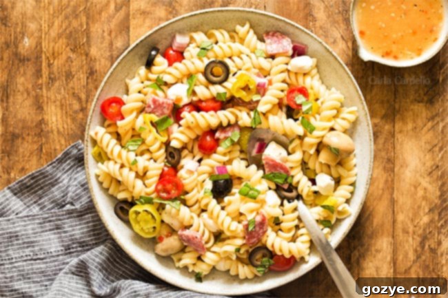 Large bowl of Antipasto Pasta Salad with a serving spoon, ready for a gathering