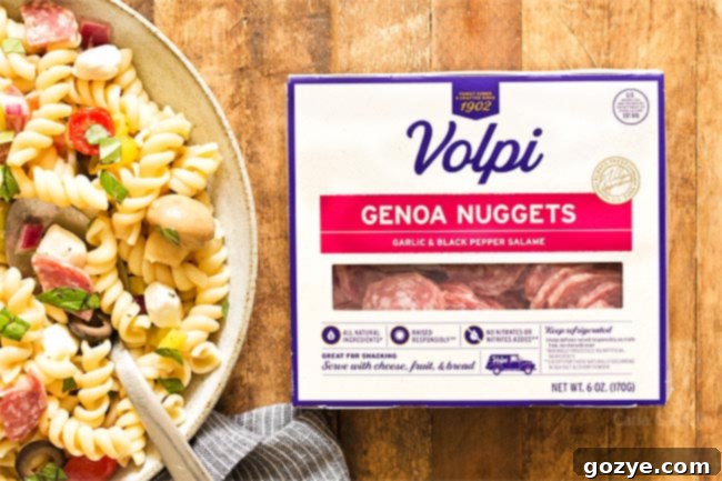 Volpi Genoa Garlic and Black Pepper Salami in its packaging, placed next to a bowl of Antipasto Pasta Salad
