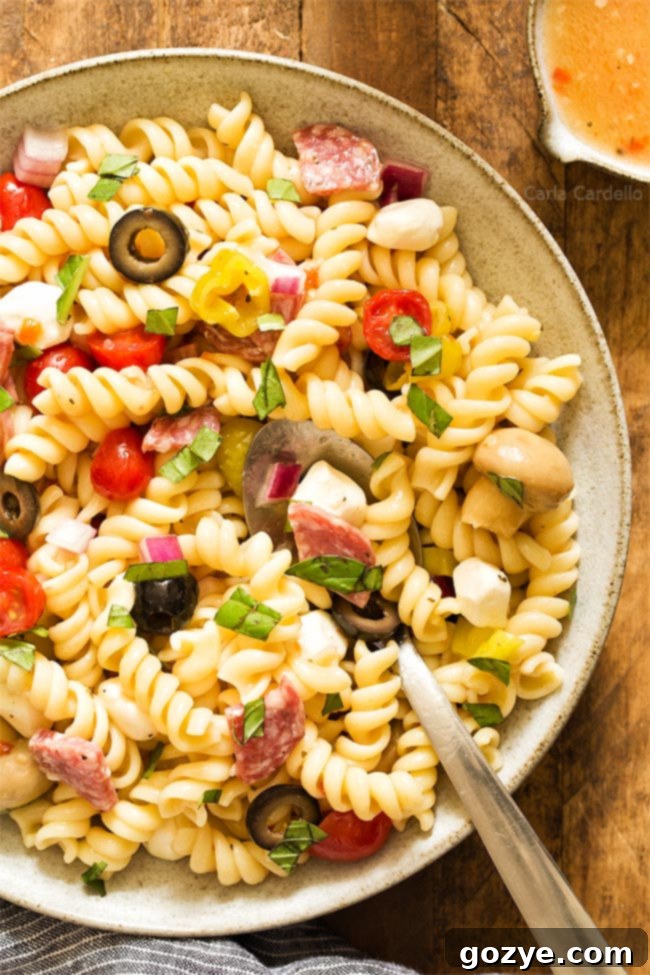 Close-up of a bowl of Antipasto Pasta Salad, glistening with Italian dressing and ready to be served