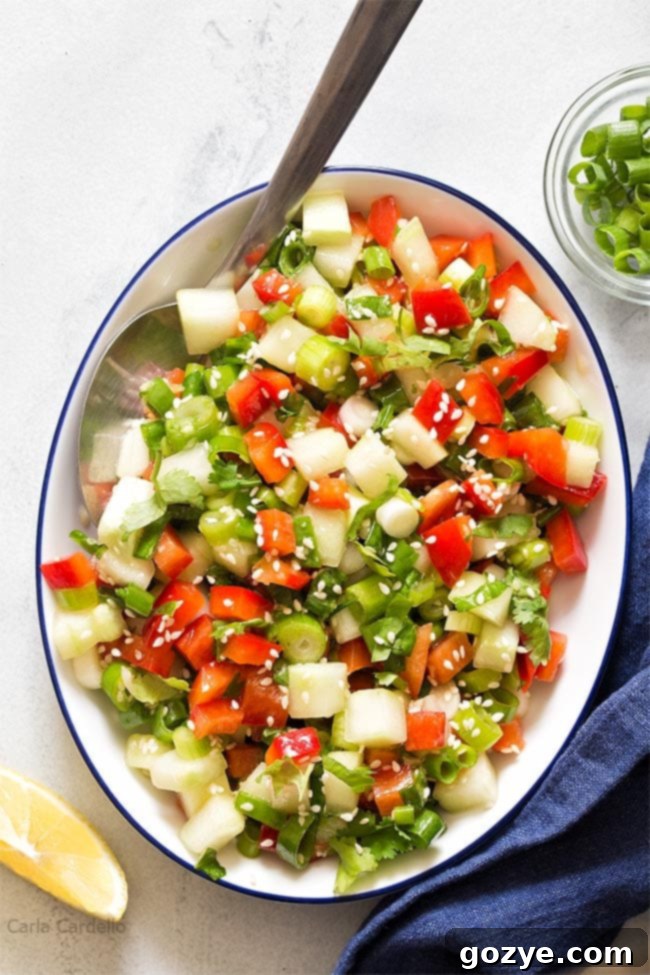 White bowl filled with vibrant green onion salad, showcasing sliced green onions, diced cucumber, and red bell pepper