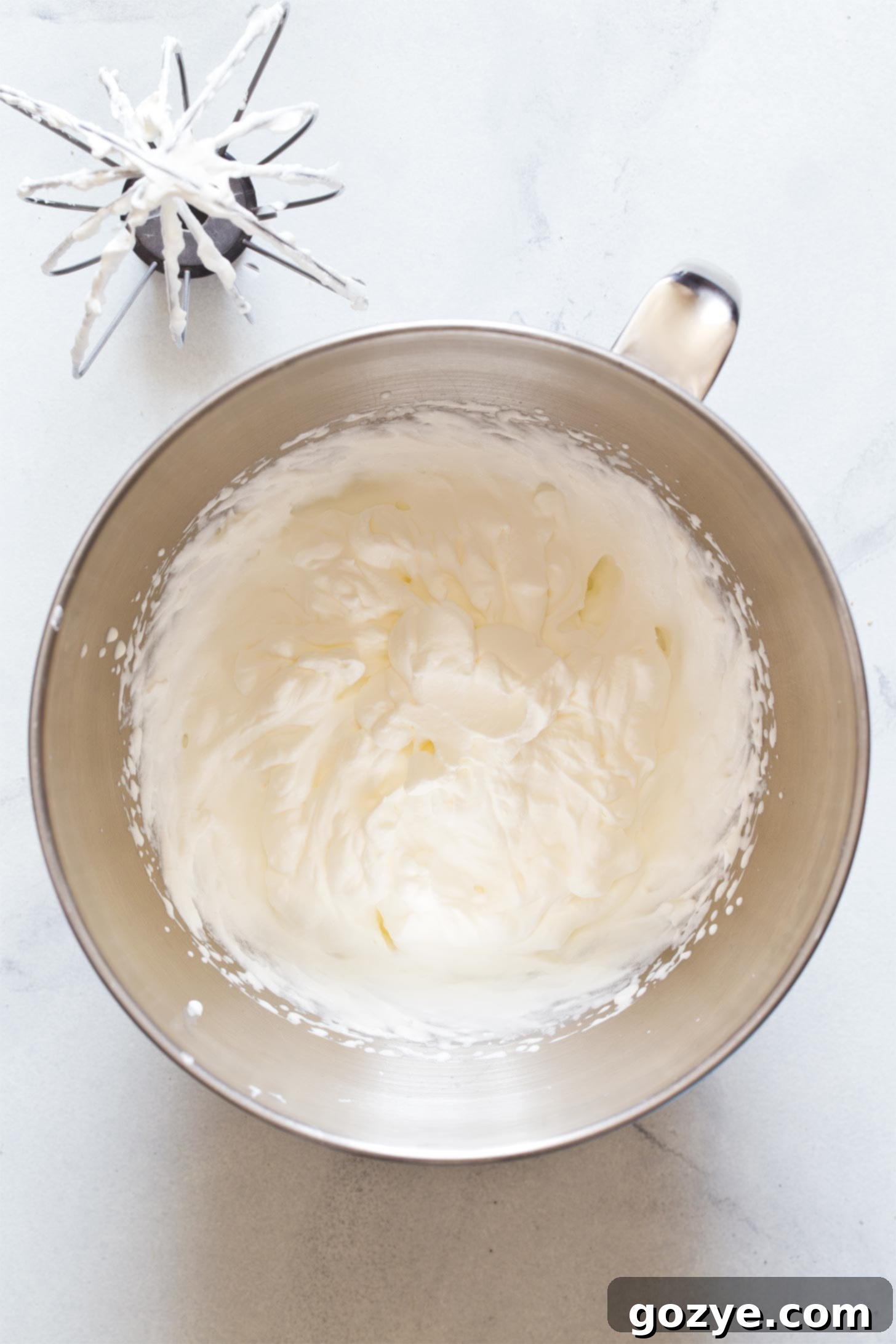 Quick No-Bake Cheesecake Bites 7 Heavy cream being whipped in a stand mixer with a whisk attachment to create whipped cream