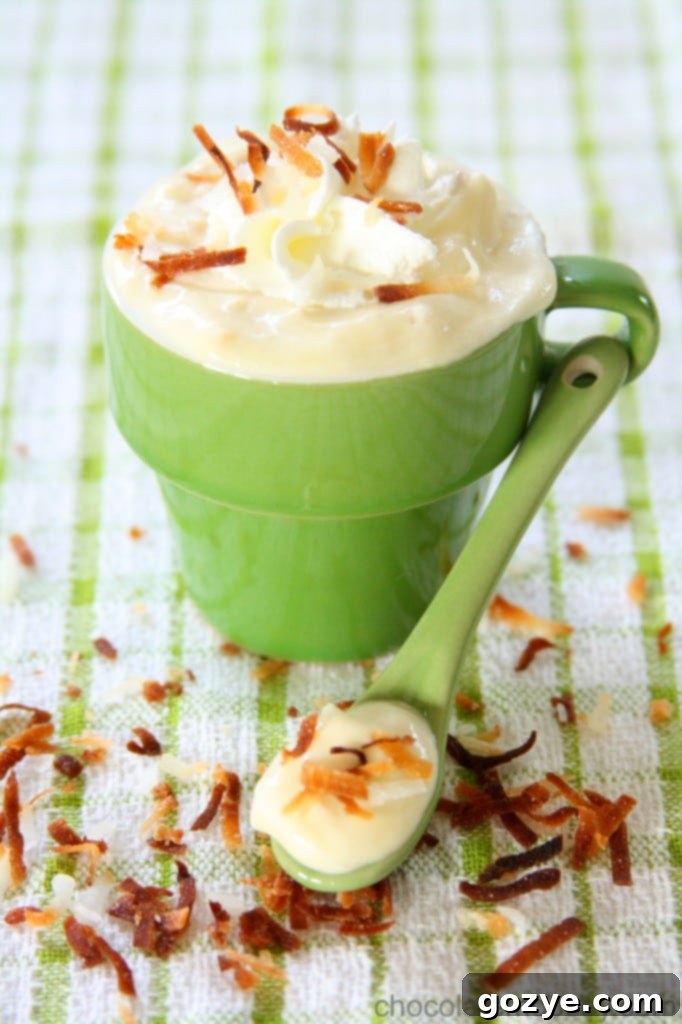 Creamy Coconut Pudding in a glass with whipped cream and toasted coconut on top