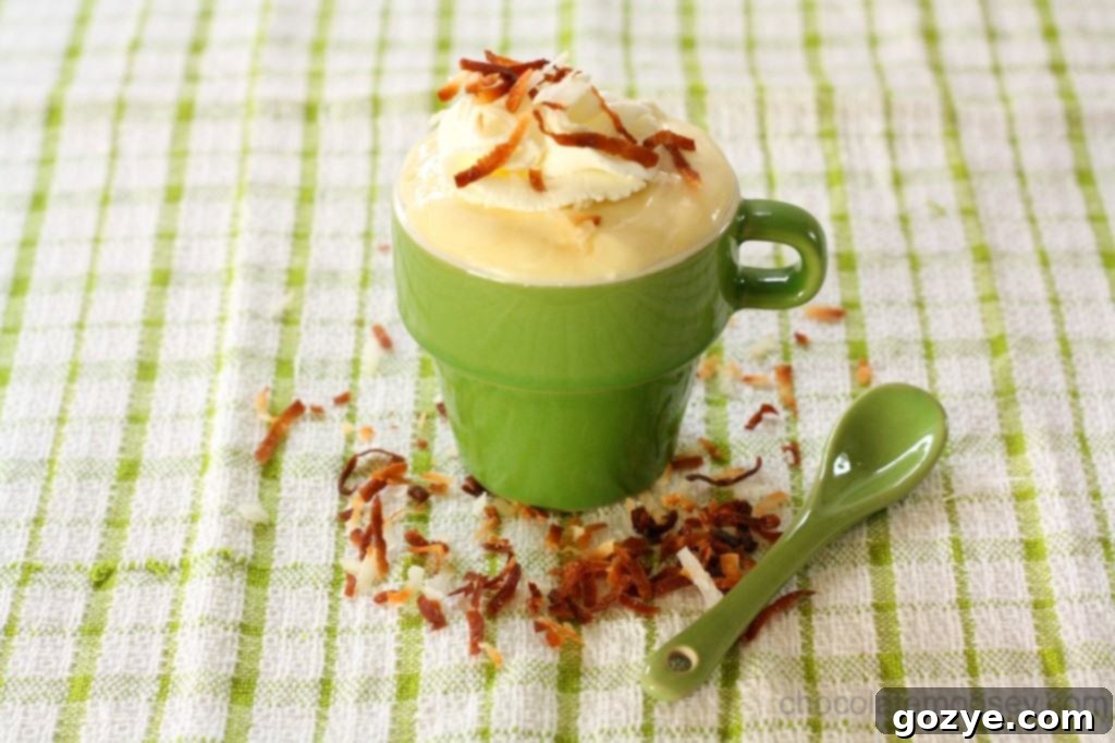 A close-up of a serving of Coconut Cream Pudding topped with whipped cream and toasted coconut