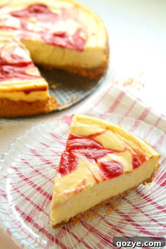 A slice of strawberry swirl cheesecake on a plate, showcasing the beautiful red swirl and creamy texture.