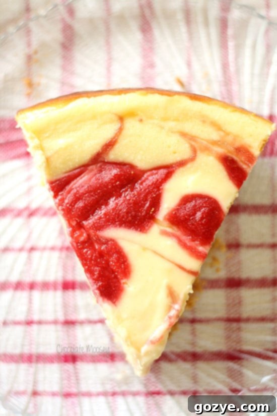 Another perspective of a slice of strawberry swirl cheesecake on a white plate.