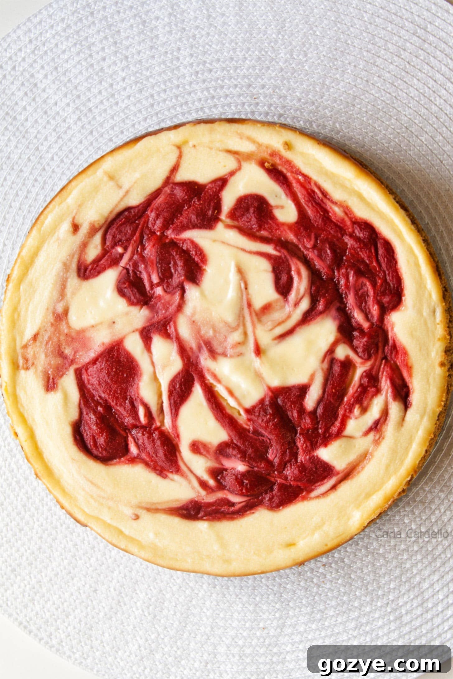 A top-down view of the Strawberry Swirl Cheesecake, showing the intricate red swirls against the white background.