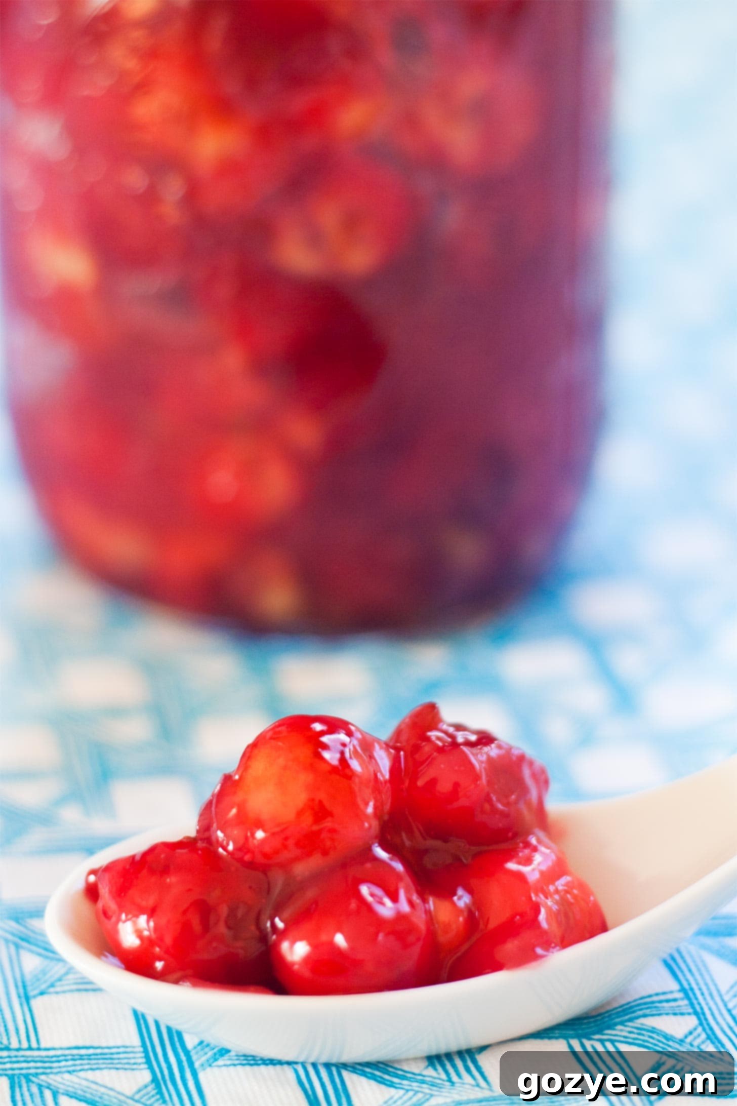 Homemade Cherry Pie Filling on a white spoon, showing its vibrant red color and texture
