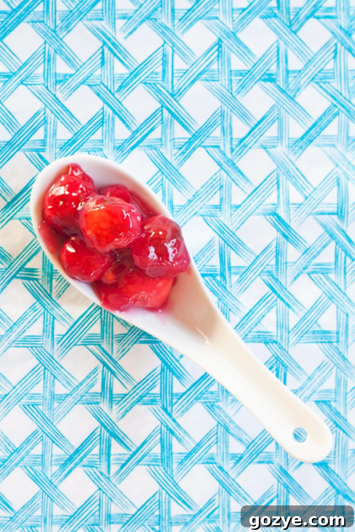 Close-up of sour cherry pie filling on a white spoon, showing thickened texture