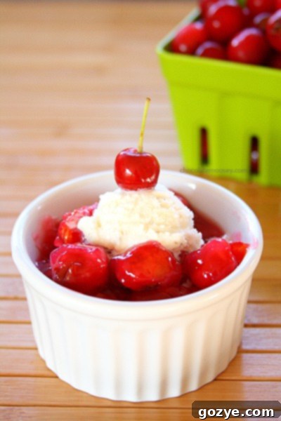 Overhead shot of a ramekin filled with warm, bubbling single serving cherry pie filling and a spoon, inviting indulgence