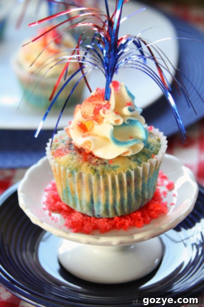 Red, White, and Blue Firecracker Cupcakes topped with swirled buttercream and Pop Rocks, perfect for Fourth of July.