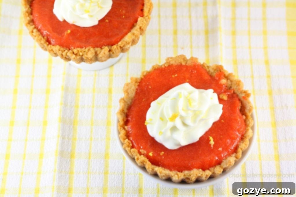 Close-up of Golden Oreo Cherry Curd Tartlettes, showcasing the vibrant cherry curd and fluffy whipped cream.