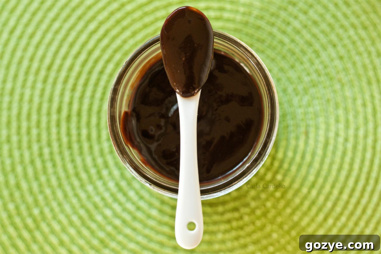 Spoon resting on top of a jar filled with smooth Nutella sauce
