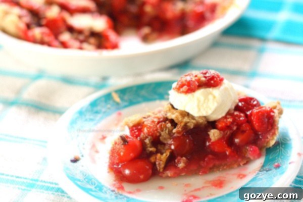 A delicious slice of Cherry Crumble Pie with a scoop of ice cream on a plate, highlighting the streusel topping and cherry filling.
