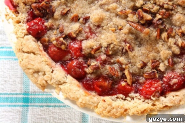 A serving of Cherry Crumble Pie, showing the rich red cherry filling peeking out from under the streusel.