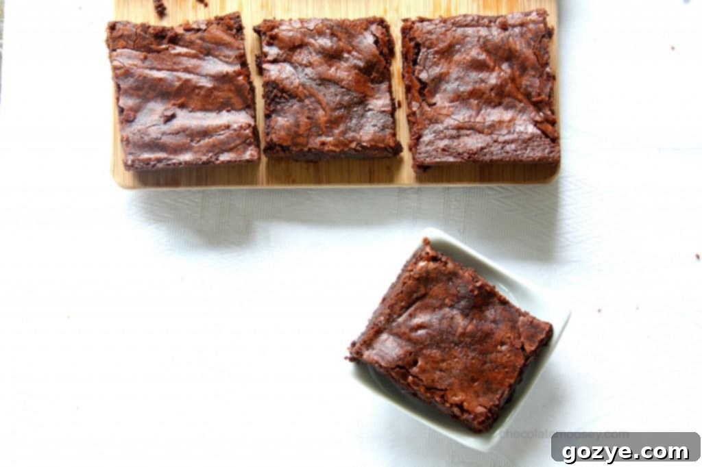 Brownie batter being poured from a saucepan into a square baking pan