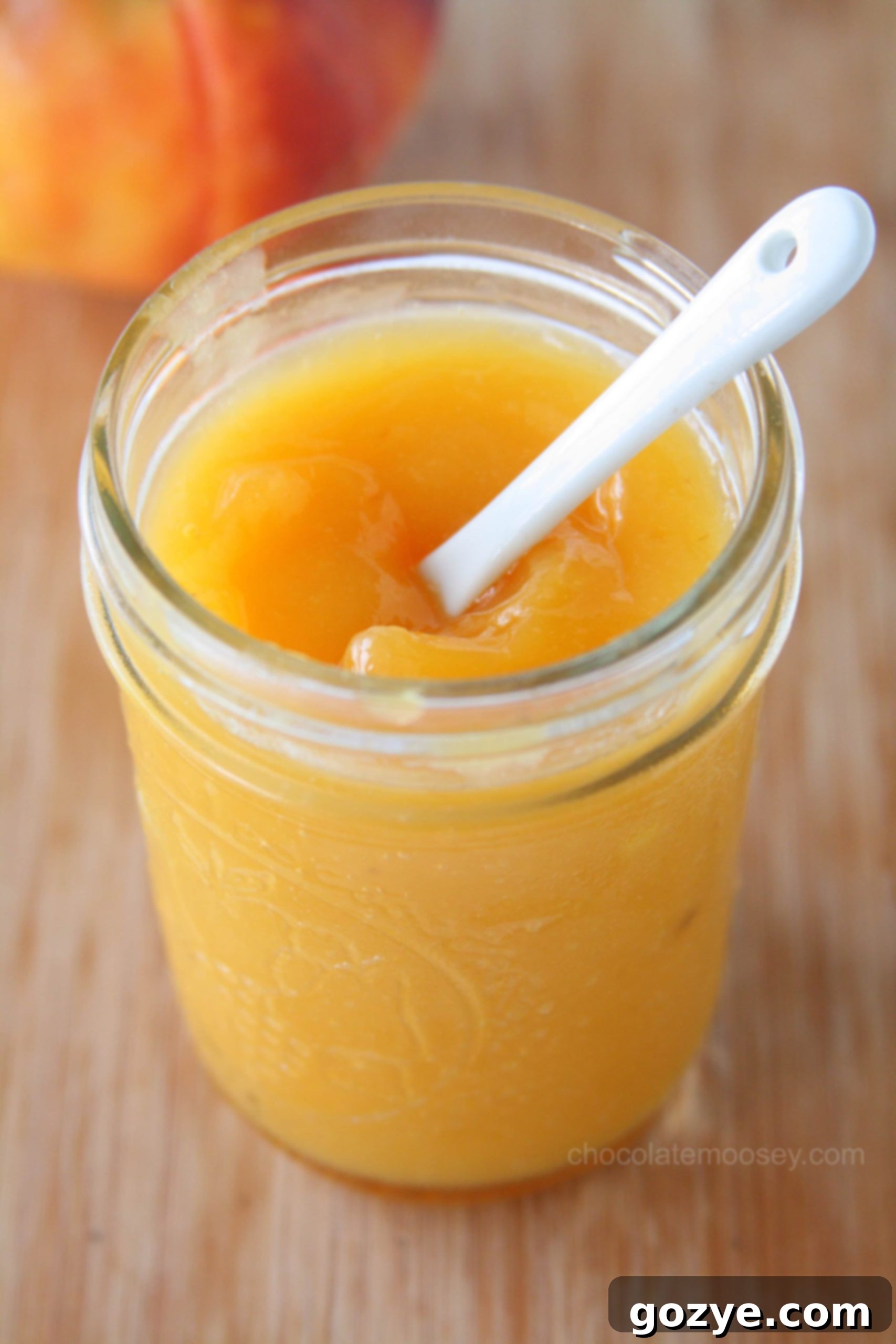 Peach Curd in a jar with white spoon, ready to be enjoyed