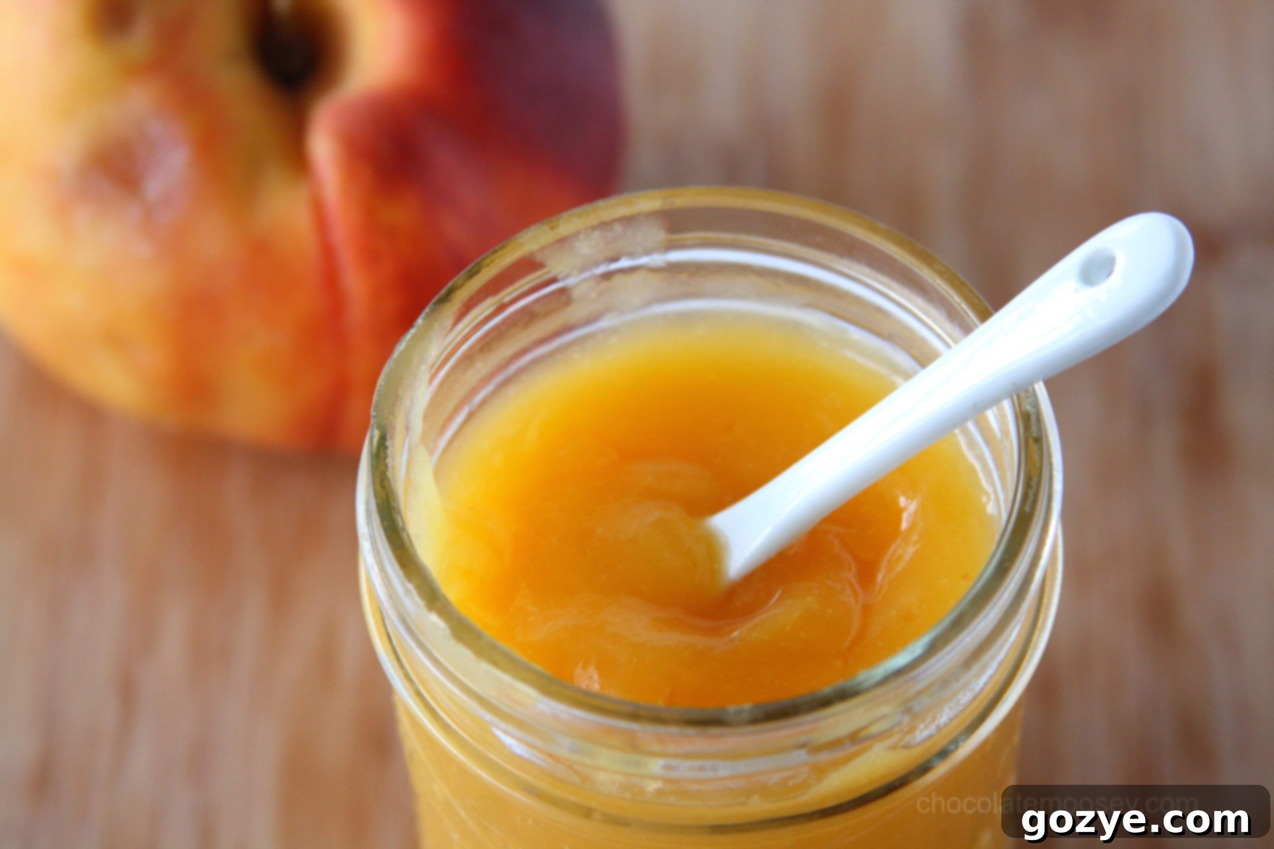 Peach Curd in a decorative jar with a white spoon, showing its creamy texture