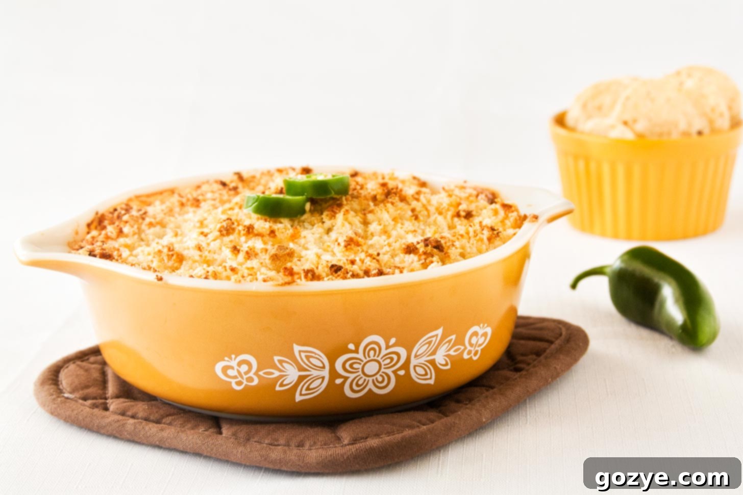 Jalapeno Popper Dip with bacon in a yellow casserole dish, garnished with fresh cilantro.