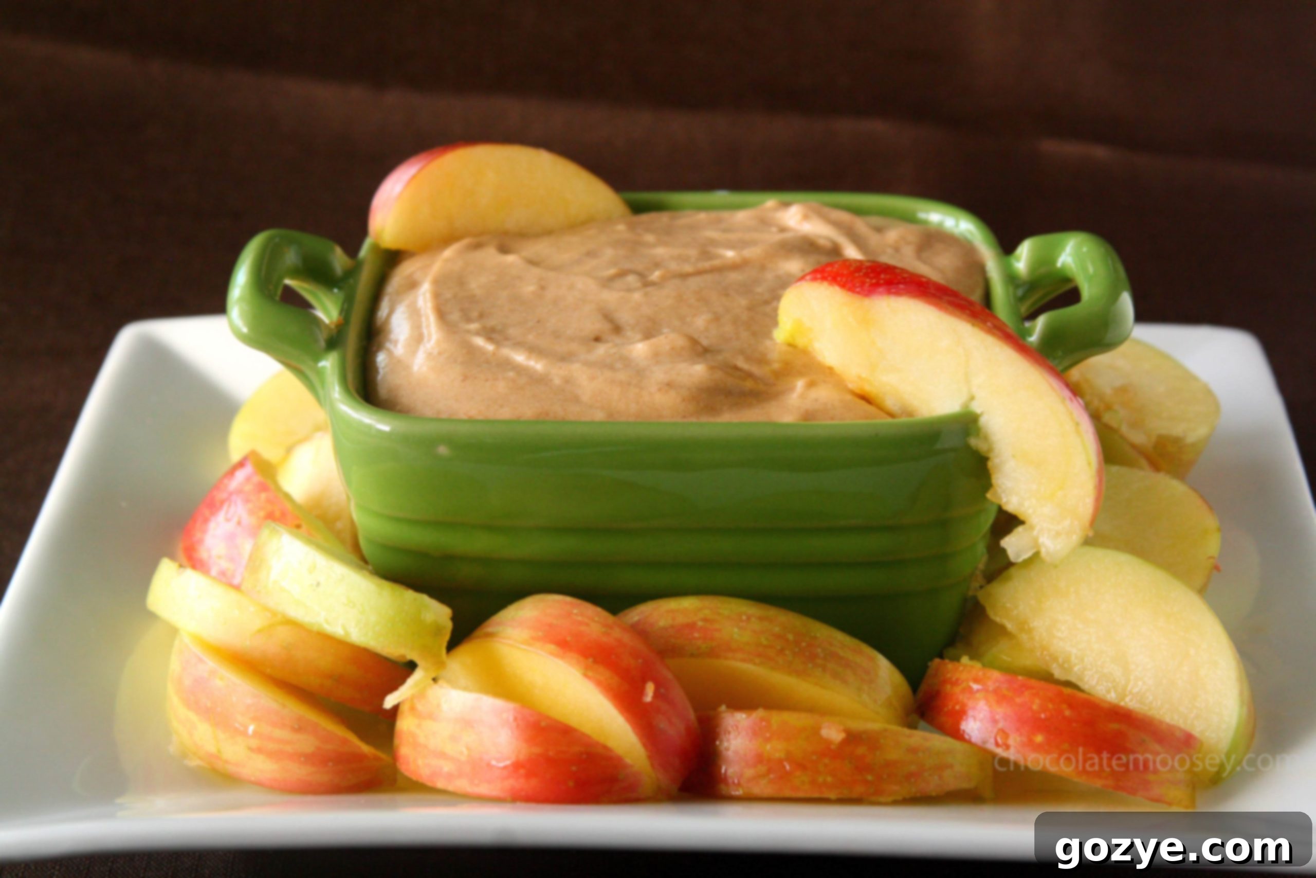 Dippable Caramel Apple Cheesecake 4 Overhead shot of a green bowl filled with caramel apple cheesecake dip, garnished with a drizzle of caramel