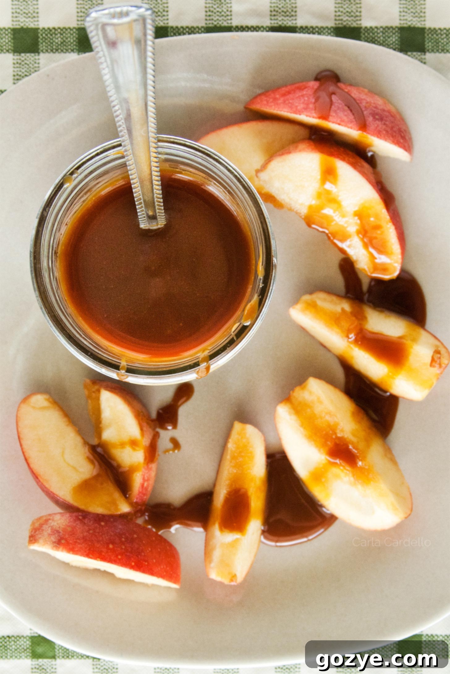 Jar of caramel sauce on plate with apple slices