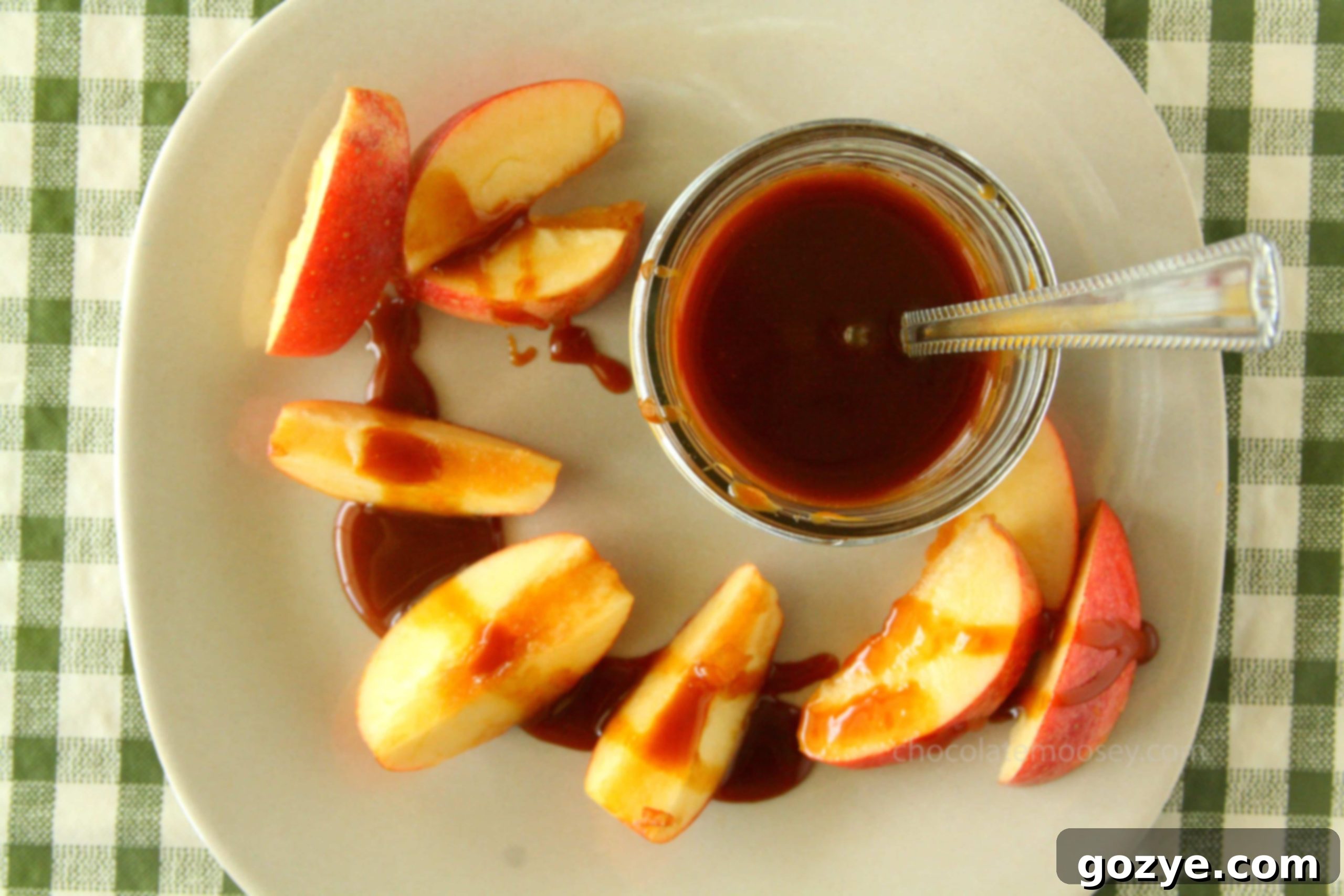 Jar of caramel sauce on plate with apple slices