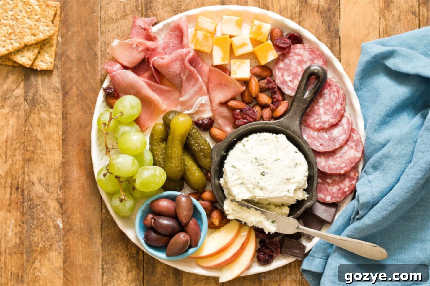 A vibrant small charcuterie board for two featuring cheeses, meats, and fruits on a white plate