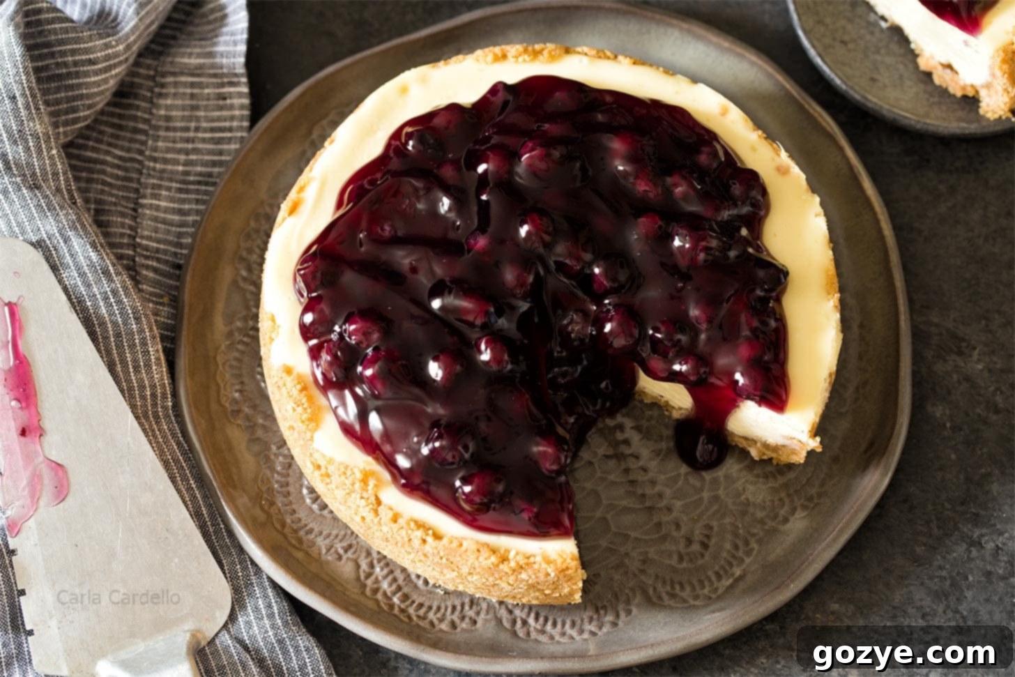 Overhead shot of a 7 inch cheesecake with one slice expertly cut out, revealing the creamy interior.