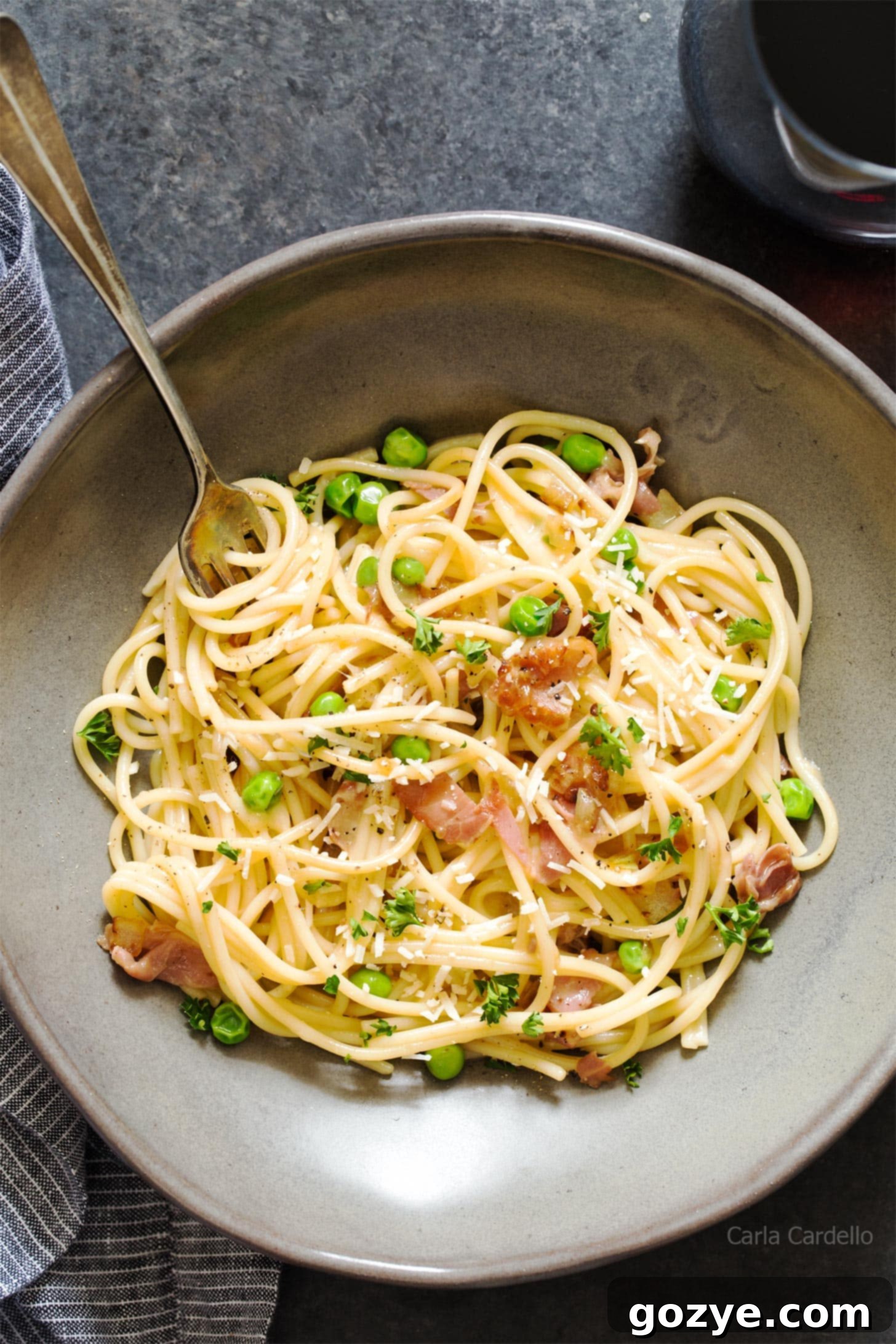 Close up of prosciutto pasta in grey bowl with fork