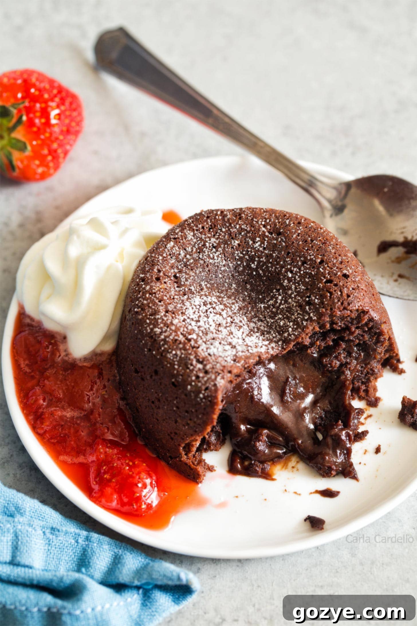 Mini Lava Cake oozing out onto plate with whipped cream and strawberry sauce