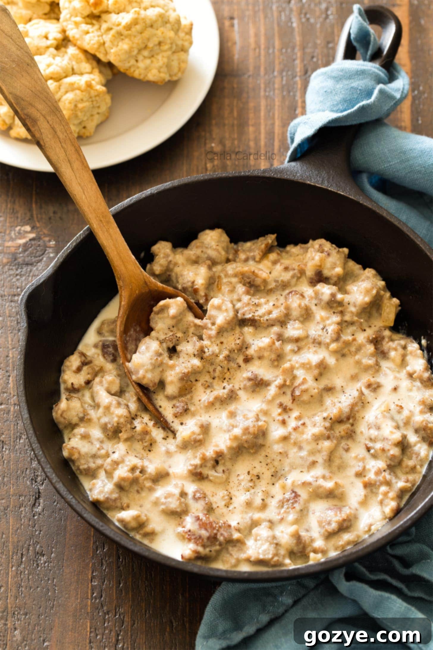 Sausage gravy in cast iron skillet with wooden spoon, perfectly browned and thick